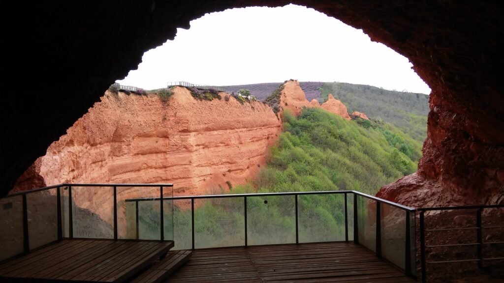 Red and orange clay mountains and mining tunnels with green forests in Las Médulas UNESCO World Heritage Site, León Spain