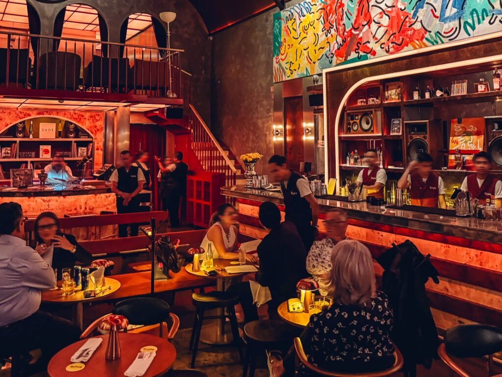 Interior of a mezcaleria bar in Mexico City with colorful mural and patrons