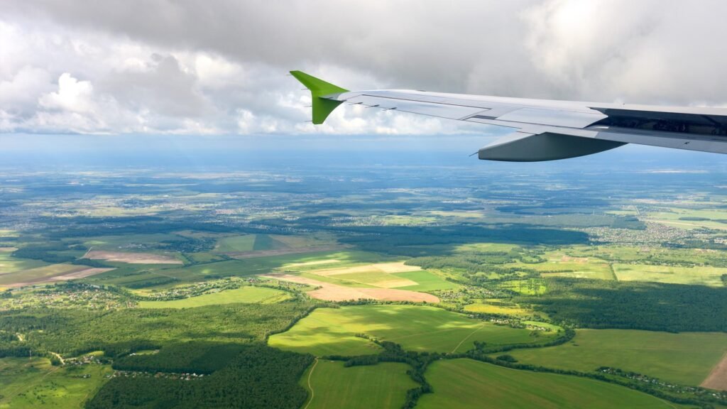Traveler looking at an airplane wing during a flight, illustrating lower-impact flight choices
