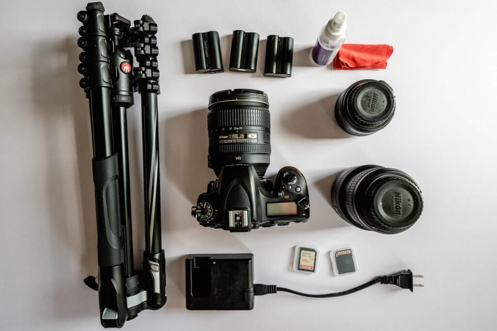 beginner travel photography kit flat lay - DSLR camera, tripod, lenses, SD cards and accessories for travel photographers