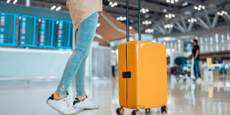 A traveler walking through an airport with one compact backpack or rolling carry-on
