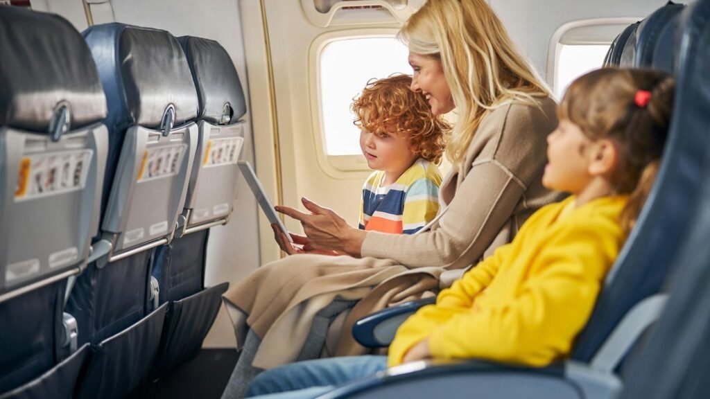 Mother and two children seated together on an airplane — practical family travel tips for managing flights with kids
