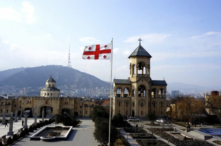 Gergeti Trinity Church with Georgian flag and Caucasus mountains - traveling in Georgia the country
