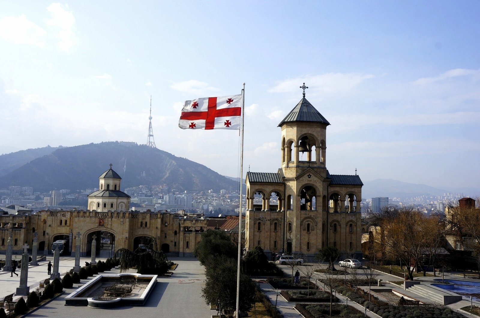 Gergeti Trinity Church with Georgian flag and Caucasus mountains - traveling in Georgia the country