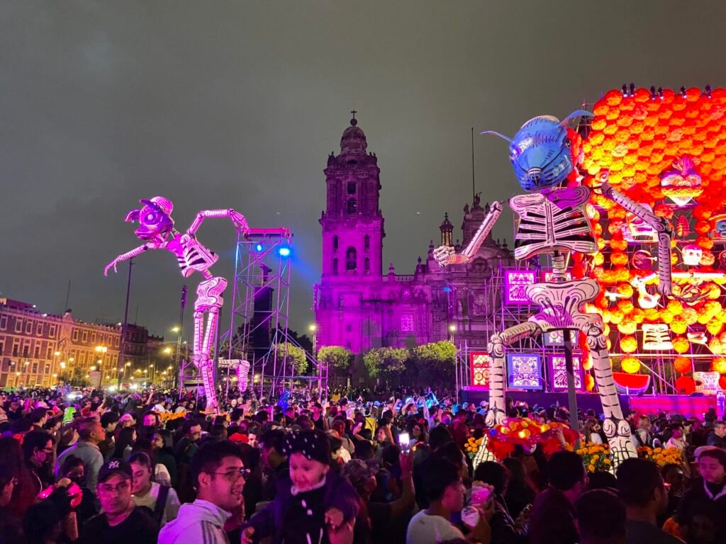Day of the Dead festival crowd with skeleton floats in Mexico City at night