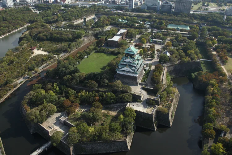 Aerial view of Osaka Castle surrounded by moat and green gardens - Japan travel guide